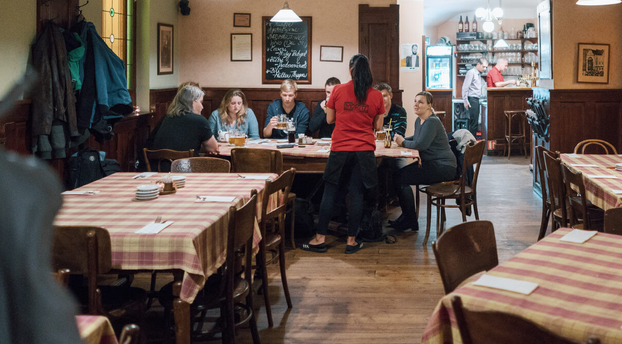 Plný sál hospody Moritz, obsluha nese pivo k dlouhému stolu